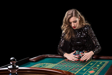 Woman playing in casino. Woman stakes piles of chips playing rou