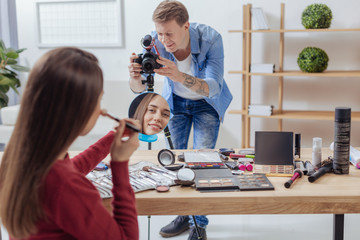 Working process. Cheerful enthusiastic experienced operator smiling while recording his friend...