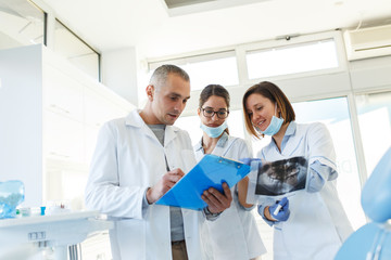 Medical dentist team in dental office discuss about practice and examining list of patients.