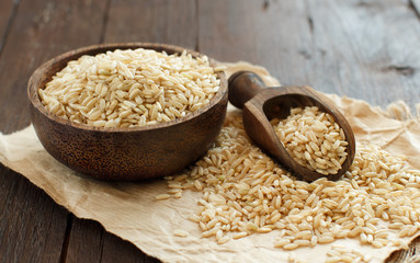 Pile of Brown rice in a bowl with a wooden spoon