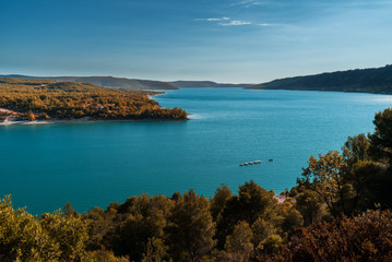 A boat navigates the turquoise blue water of a magnificent lake in Provence