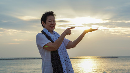 Fototapeta na wymiar Asian senior woman with hand holding sun concept of success and