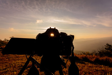 silhouette of camera with sunrise sky and mountain
