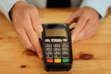 Convenient payment. Senior responsible busy man showing and touching to the cash machine and demonstrating it.