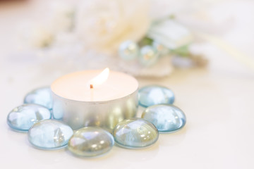 Obraz na płótnie Canvas St. Valentine's Day concept with a burning white candle and decorative glass pebbles, close up, white background