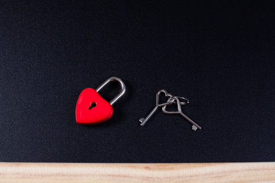 A locked red heart shaped lock with a key stuck on background.