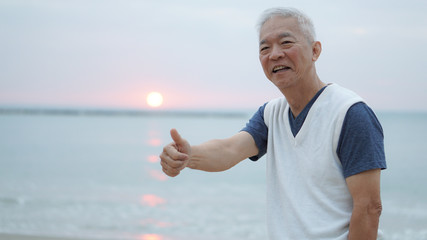 Asian senior man thumbs up at sunrise financial worry free