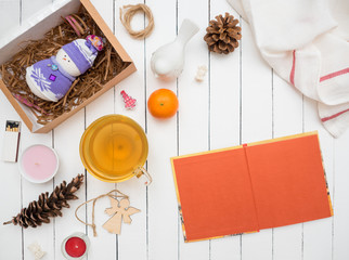 Glass cup of green tea, open notebook and mandarin on a white wooden table