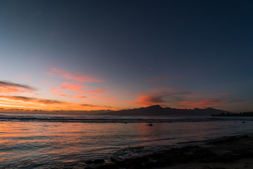 Fototapeta na wymiar A sky on fire during a sunrise on an island