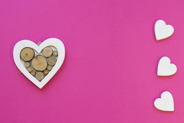 St. Valentine's Day or Anniversary concept pink background with wooden hearts, top view