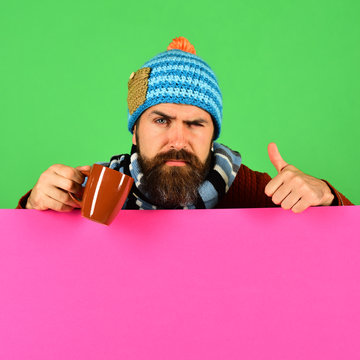 Hipster with tricky face holds tea or coffee cup