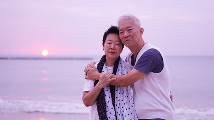 Asian senior couple dating at sunrise sea