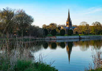 Fototapeta na wymiar Church reflecting in lake at Clumber Park, a National Trust estate in Nottinghamshire, UK