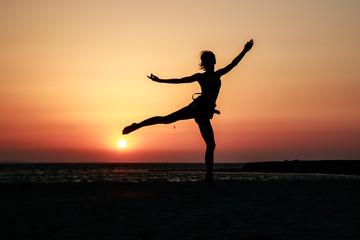 Woman girl model with slim figure like ballet dancer silhouette on the sea background, orange sunset sky and sea background, Africa, Egypt. Red Sea. Awesome people and nature picturesque scenery