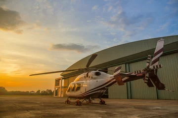 Foto auf Acrylglas Silhouette des Hubschraubers auf dem Parkplatz oder der Landebahn mit Sonnenaufgangshintergrund, Dämmerungshubschrauber auf dem Hubschrauberlandeplatz © saelim