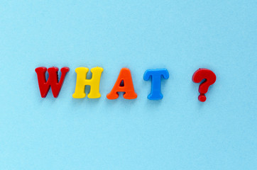  question "what ?" of plastic magnetic letters on blue background