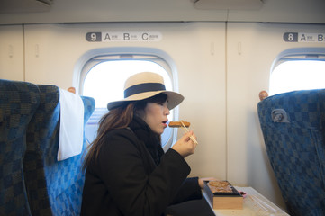 Woman passenger is eating tonkatsu box set while traveling by Shinkansen in Japan.