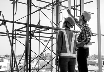 Black and white picture of professional Asian engineering team wearing safety helmet talking about...