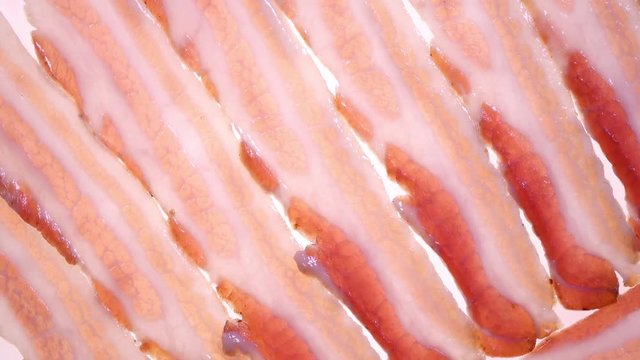 Amazing top view of fresh sliced bacon with backlight close up, rotating contra clockwise. Vibrant natural food background with excellent texture in 4k, 3840x2160, clip.