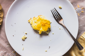 fork and pieces of half-eaten eggs on a plate. empty box with a spoon from the sauce