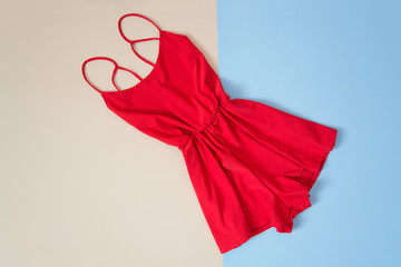Red romper, tender pink and blue background. Fashionable concept