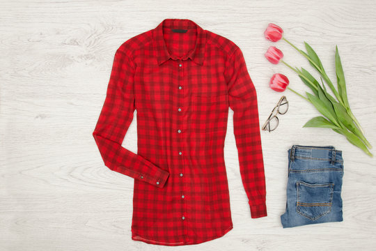 Fashion concept. Red blouse, jeans, lipstick and pink tulips. Top view