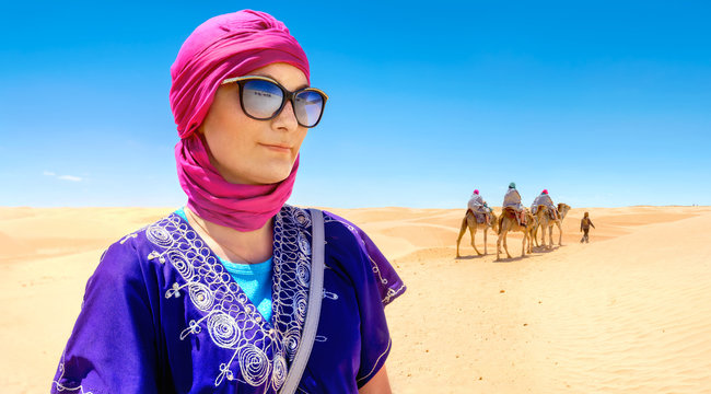 Beautiful woman in arabic traditional clothing against Sahara desert background. Tunisia, North Africa