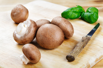 Braune Champignons mit Messer auf Holzbrett