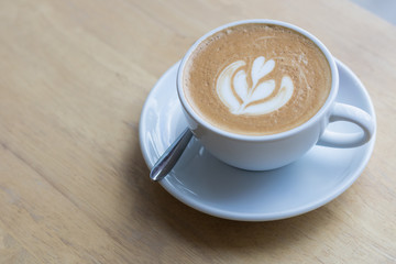 Hot coffee latte with beautiful foam art on glass table.Indoor cafe