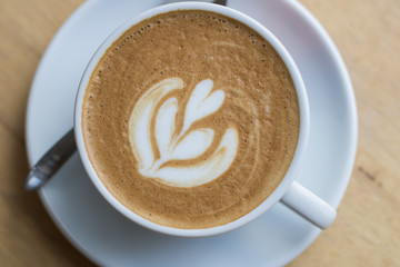 Hot coffee latte with beautiful foam art on glass table.Indoor cafe