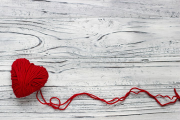 Heart in the form of a string of threads from which a red sweater knits. Valentines day concept.