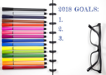 2018 Goals text on white sketchbook with color pen and eye glasses, Top View/Flat Lay