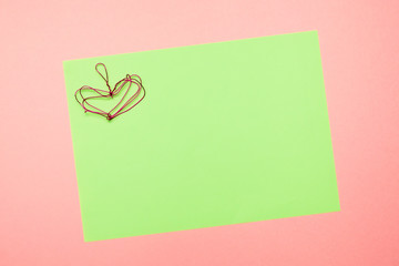 Valentines Day card, wedding card. Red heart made of folded wire on textured green and pink paper background. Empty blank for text and design.
