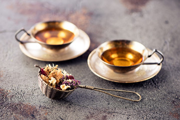 Cups herbal tea and strainer on a concrete background