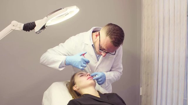 Lip injection plastic surgery. Young male doctor doing lip augmentation