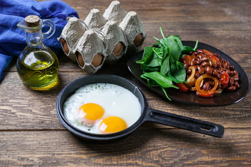 The pan fried eggs, haricot stewed in tomato sauce and fresh spinach. Concept of a healthy breakfast.
