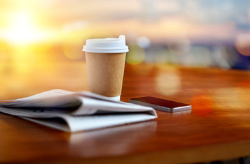 coffee cup, smartphone and newspaper on table