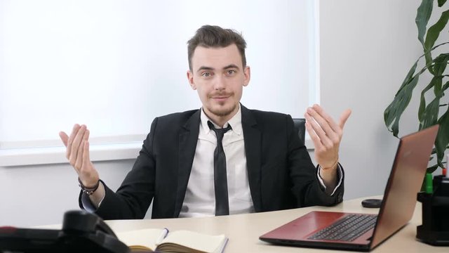 Young businessman in suit sitting in office and showing come here or come on gesture 60 fps