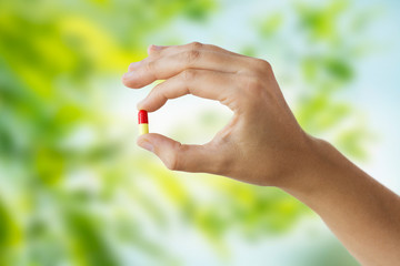 close up of hand holding capsule of medicine