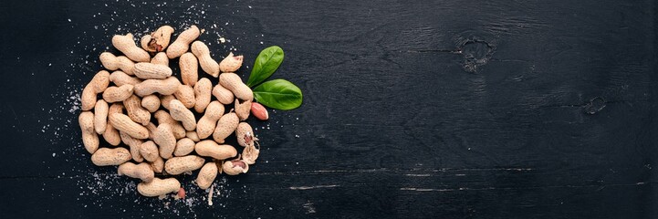 Peanuts on a dark wooden background. Healthy snacks. Top view. Free space for text.
