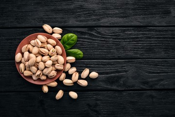 Pistachio nuts on a dark wooden background. Healthy snacks. Top view. Free space for text.