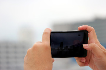 Human hands holding and touching a smartphone screen to take a photo.