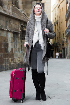young girl in hood and coat with baggage