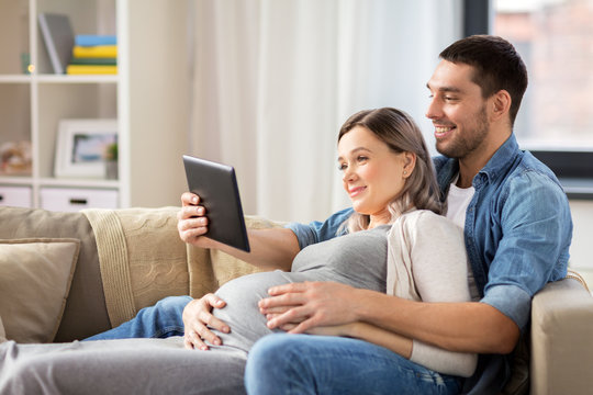 man and pregnant woman with tablet pc at home