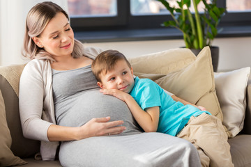 Obraz premium happy pregnant mother and son hugging at home