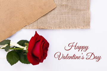 Red rose on the white background with Happy Valentine's Day text, old yellow paper and piece of natural jute