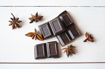 Close up of annis and dark chocolatea on white wooden table.