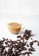 Annis and dark chocolate on the white wooden background with cup of coffee.