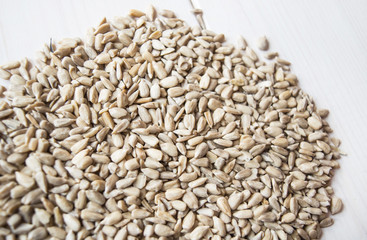Raw food. Close up of seed for sunflower on white wooden background.