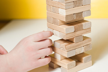 The child plays in board game falling tower of wooden blocks